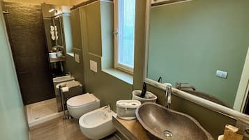 Une salle de bain moderne avec un grand miroir, un lavabo en pierre, un bidet et un espace douche.