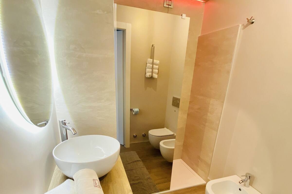 Ein modernes Badezimmer mit einem großen Spiegel, einem Holzbidet, einem Waschbecken und einer Toilette.