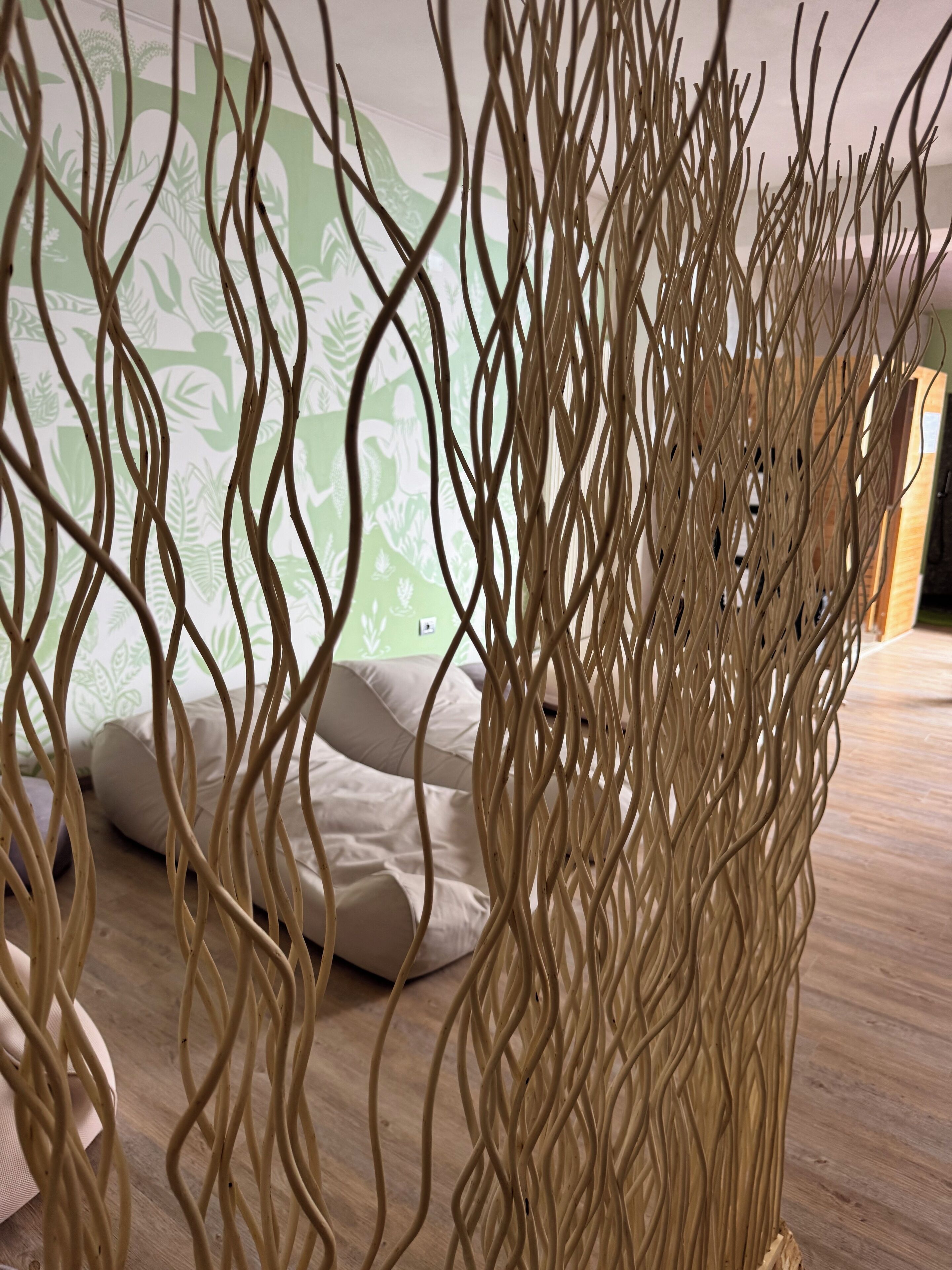 A room with a bed, pillows, and a decorative woven partition.