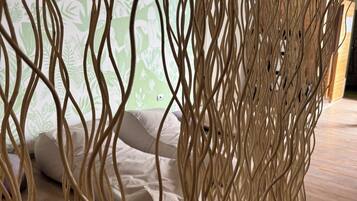 A room with a bed, pillows, and a decorative woven partition.