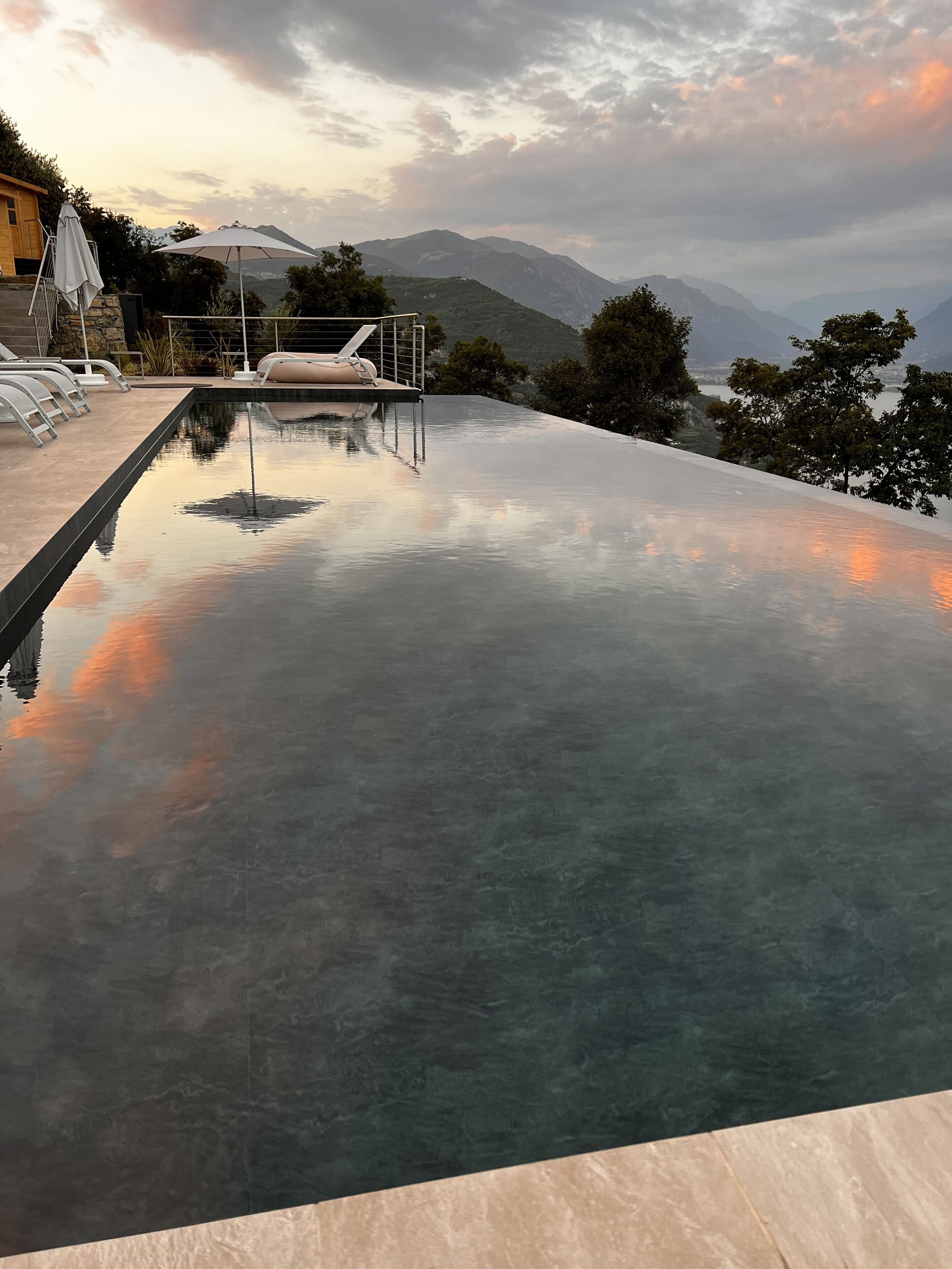 An infinity pool with a view of mountains and a sunset.