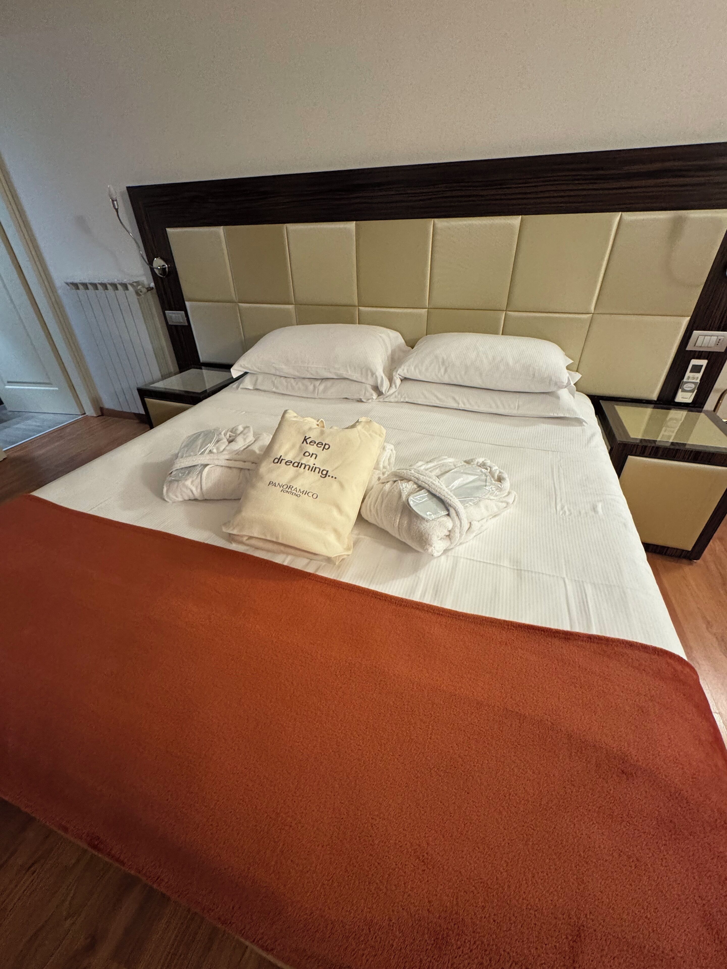Un letto rifatto con una coperta marrone, due cuscini e un asciugamano piegato.