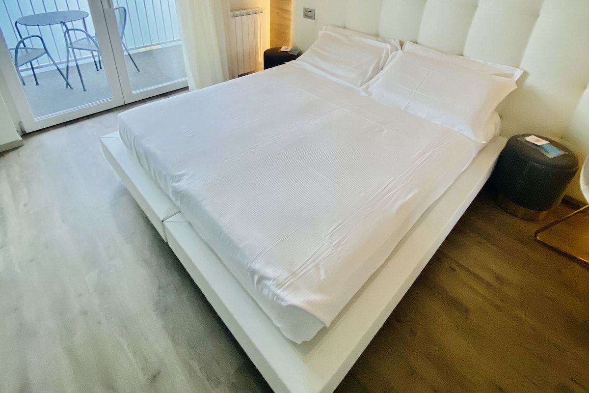 Ein modernes Hotelzimmer mit einem großen Bett, einem Balkon mit Meerblick und einer Klimaanlage an der Wand.