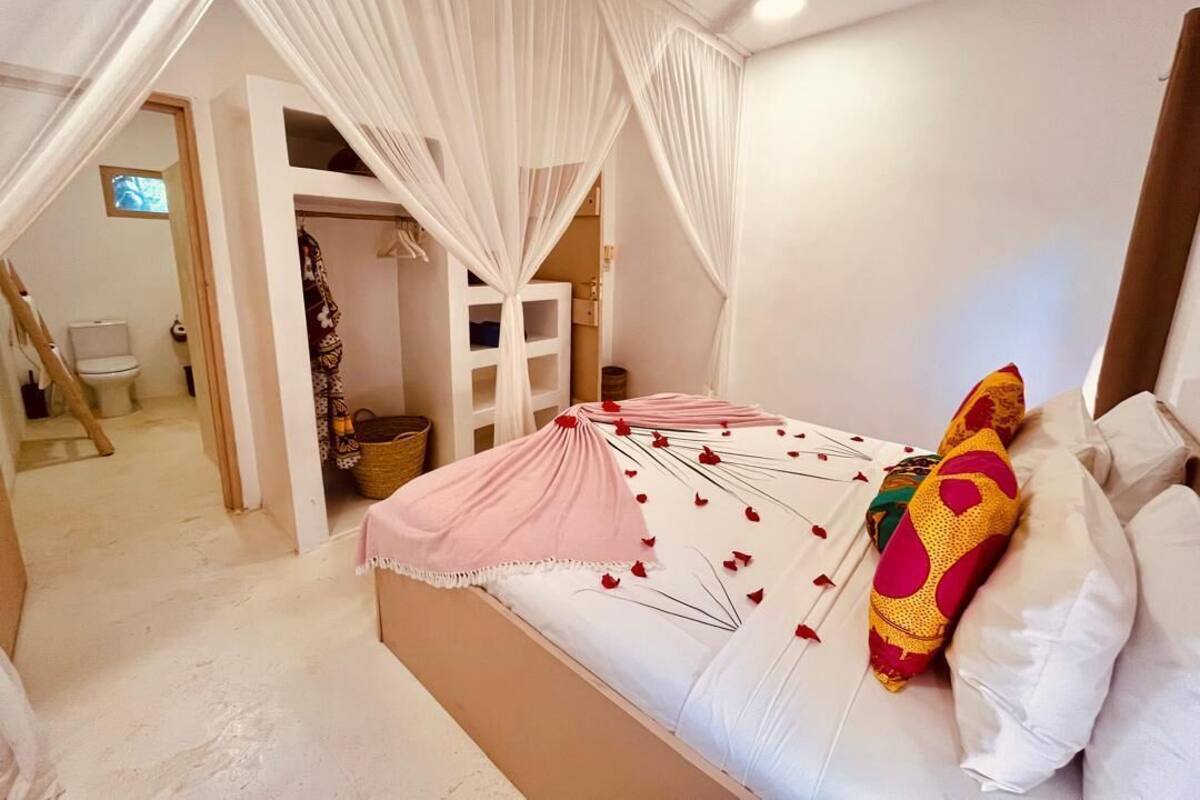 Un dormitorio con cama, cortinas blancas y ventana.