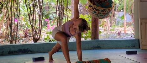 A yoga mat on the floor with a hanging hammock and a bowl.