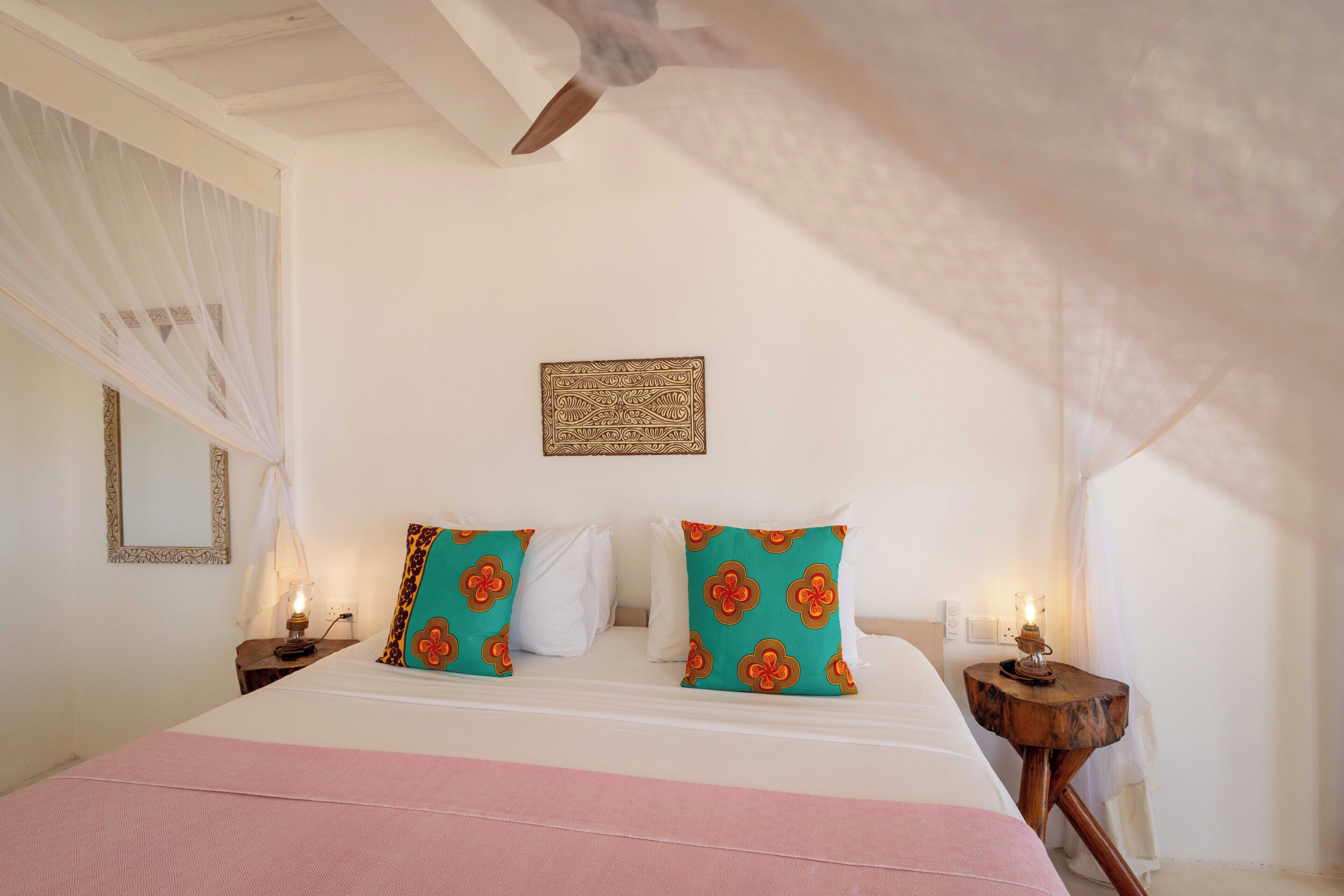 A bedroom with a bed, a nightstand, a wall-mounted lamp, and a decorative item above the bed.