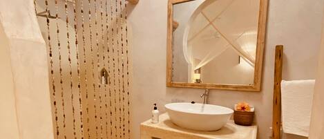 Un baño con ducha, lavamanos y espejo.
