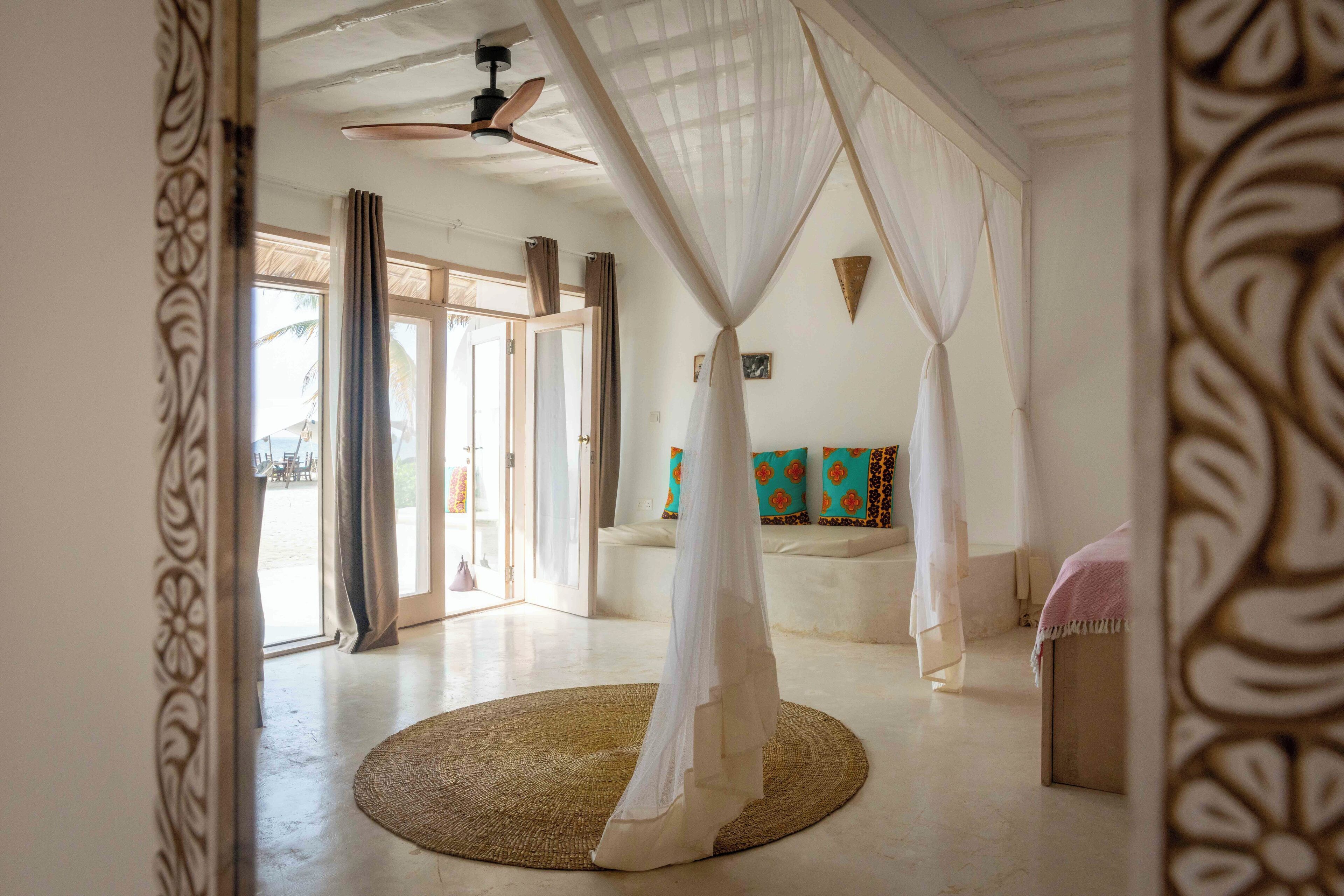 A spacious room with a large window, a ceiling fan, and a bed with a canopy.