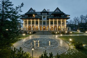 A large, multi-story building with a symmetrical facade, arched windows, and a central entrance. - Hotel Logos (Zakopane)