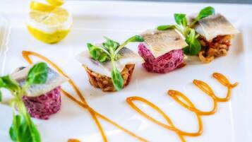 A white plate with food items, a lemon wedge, and a sauce.