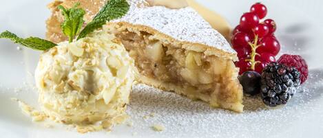 A dessert plate with a slice of apple pie, a scoop of vanilla ice cream, and fresh berries.