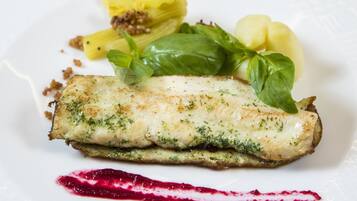 A plate with a fish fillet, green sauce, and a red sauce.