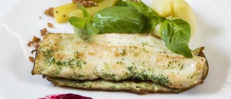 Un plato con un filete de pescado, salsa verde y salsa roja.