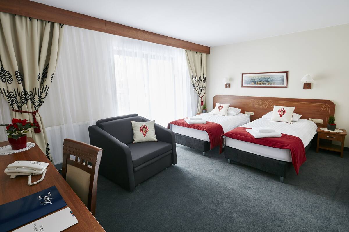 Quarto de hotel com duas camas, uma escrivaninha e uma cadeira.