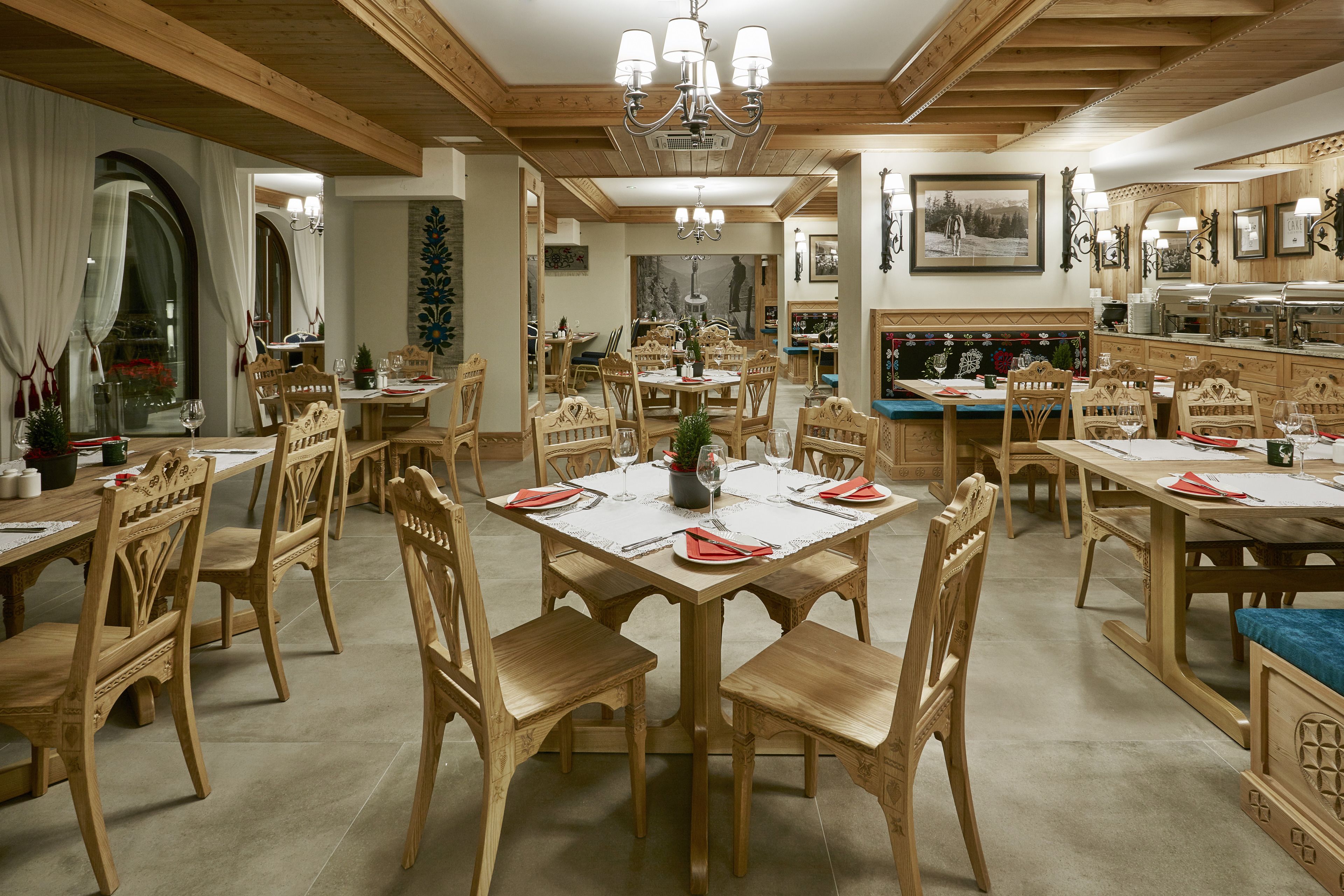 A dining area with wooden tables and chairs, a chandelier, and a buffet counter.