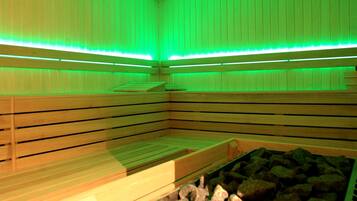 A sauna room with wooden benches and a stone basin.