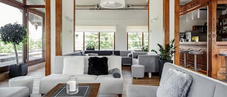 A spacious living area with a large sofa set, a coffee table, and a bar area with stools.
