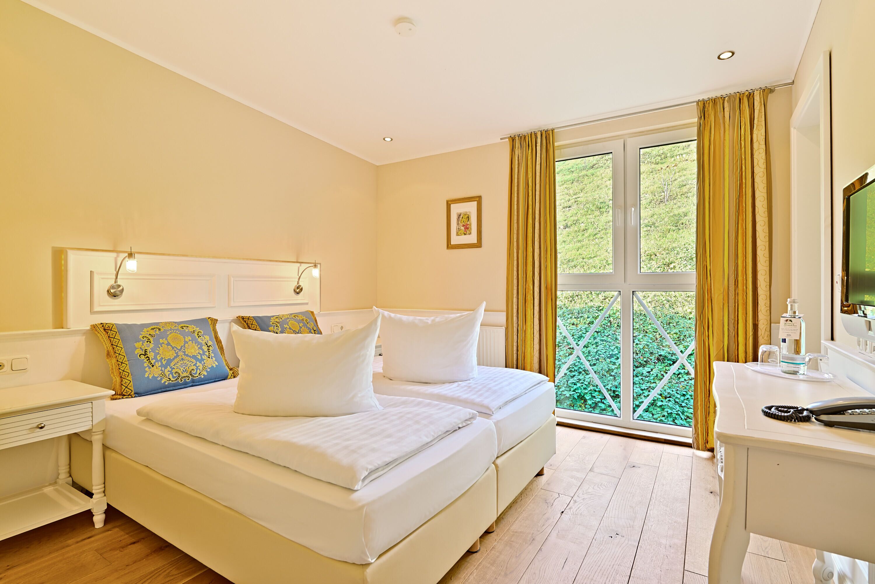 A bedroom with a bed, bedside tables, a desk, and a window with curtains.