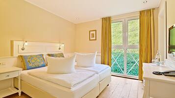 A bedroom with a bed, bedside tables, a desk, and a window with curtains.
