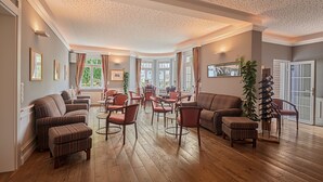 Ein geräumiges Wohnzimmer mit Kamin, mehreren Sitzgelegenheiten und großen Fenstern mit Blick ins Freie.