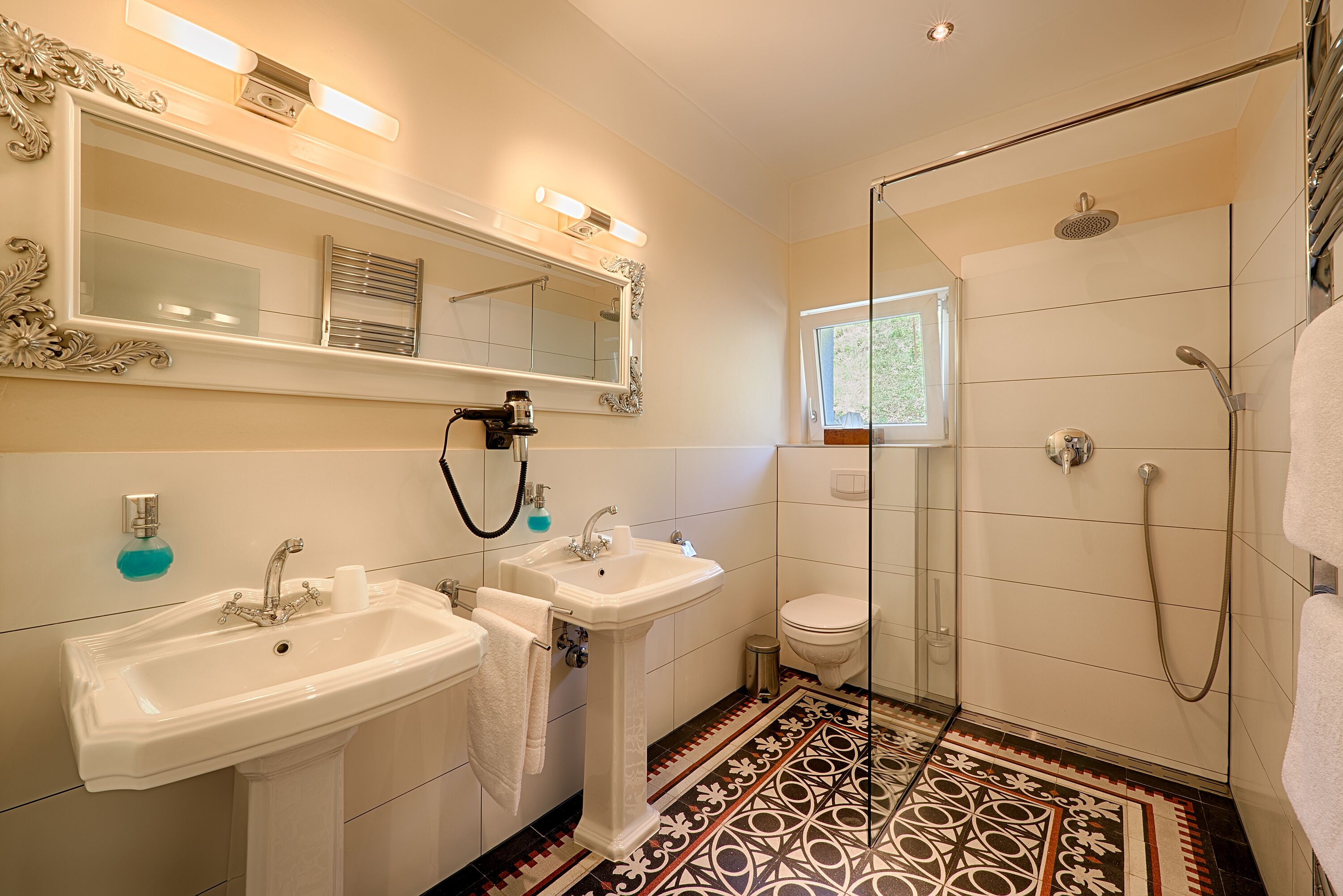 Un bagno con due lavandini, un water e una doccia.