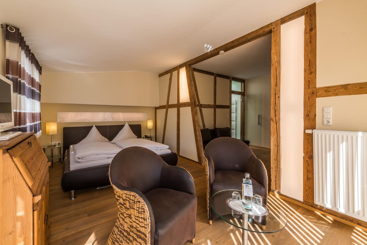 Une chambre à coucher comprenant un lit, deux fauteuils, une table en verre, un téléviseur et une armoire en bois.