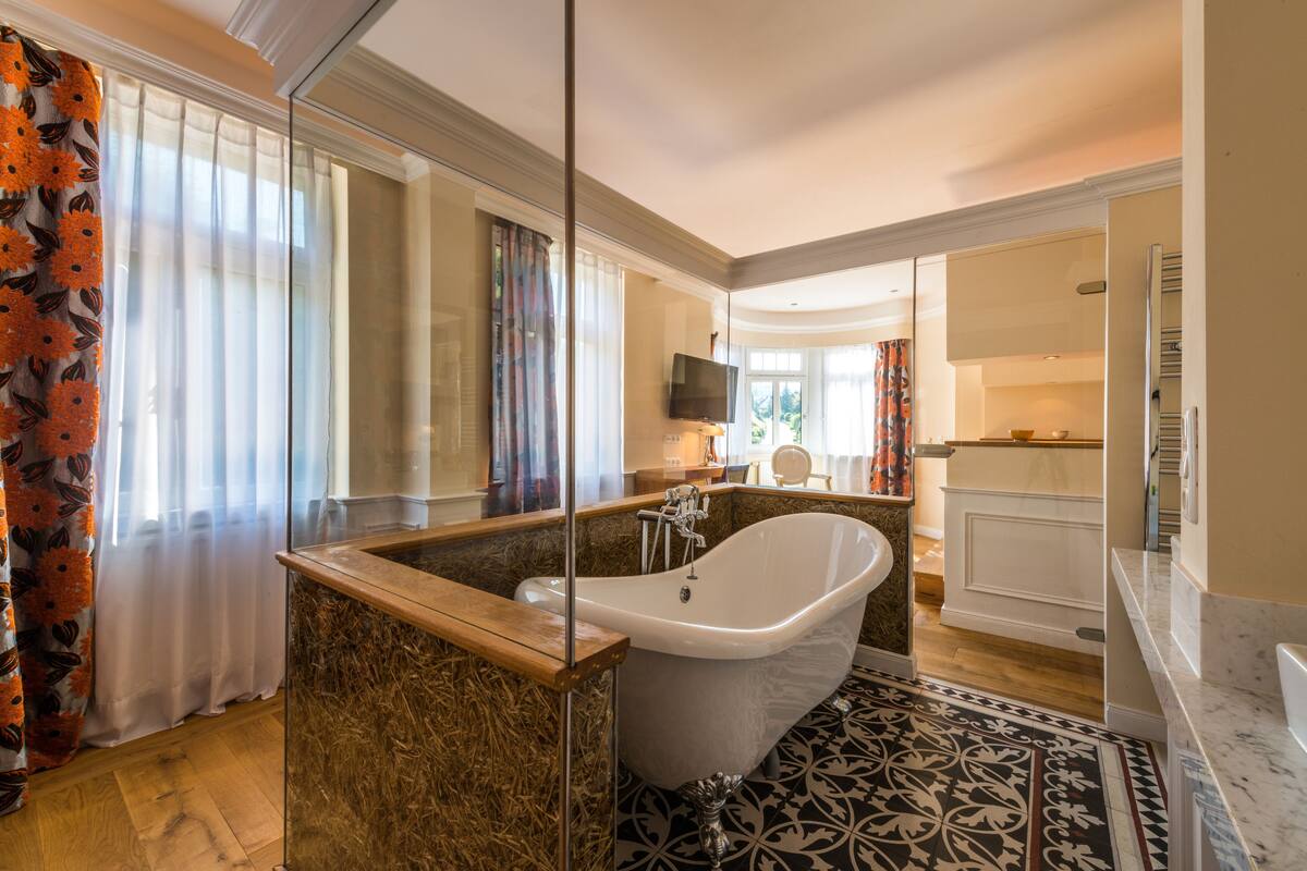 Une salle de bain moderne avec une baignoire sur pieds, un grand miroir et un carrelage décoratif.