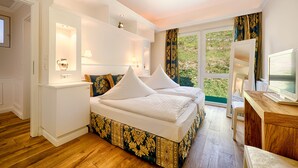 Ein Schlafzimmer mit einem großen Bett, integrierten Regalen, einem Schreibtisch und Blick auf Grünfläche.