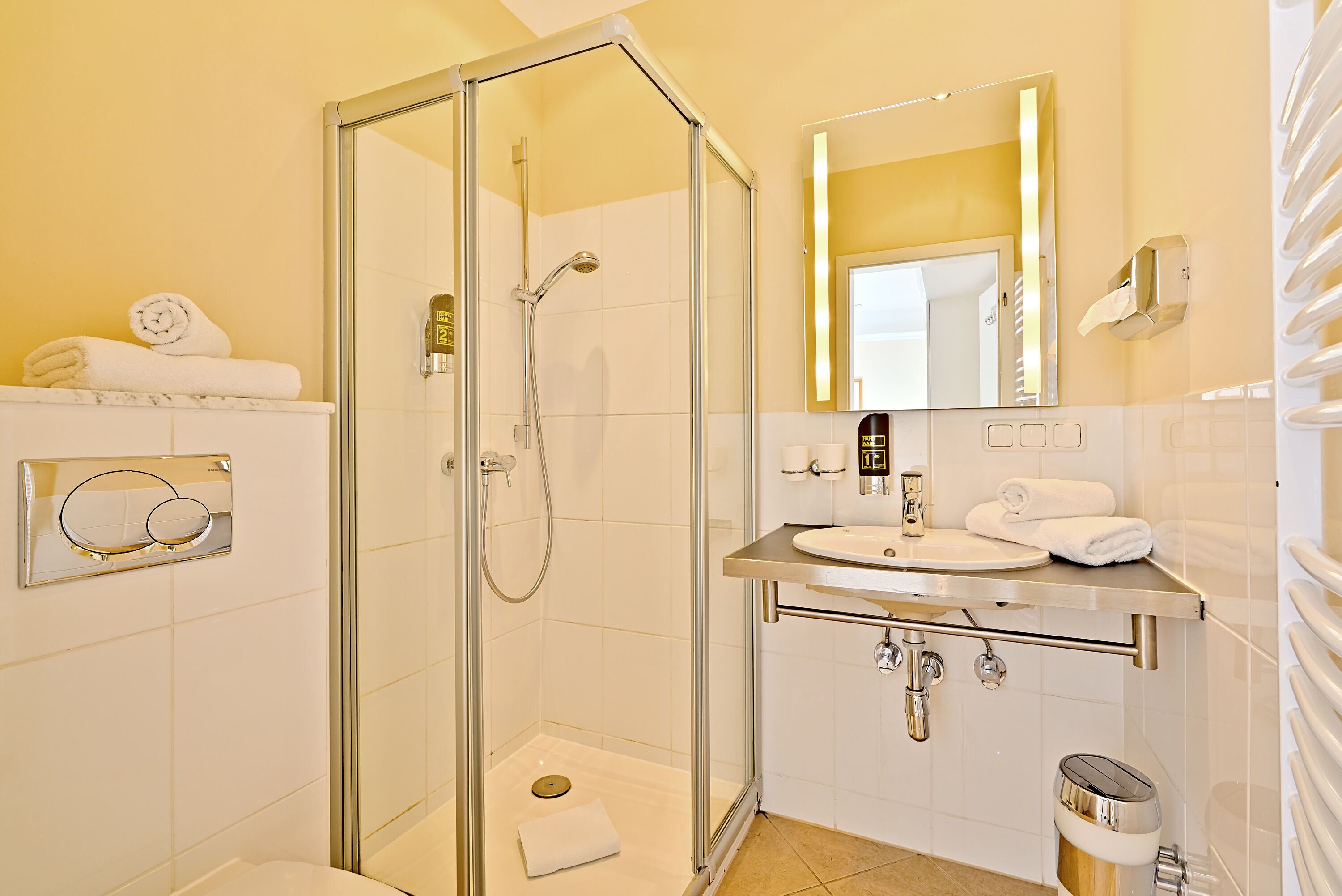 A modern bathroom with a glass-enclosed shower, a sink with a vanity, and a mirror with a gold frame.
