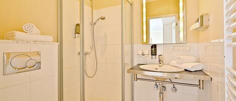 A modern bathroom with a glass-enclosed shower, a sink with a vanity, and a mirror with a gold frame.