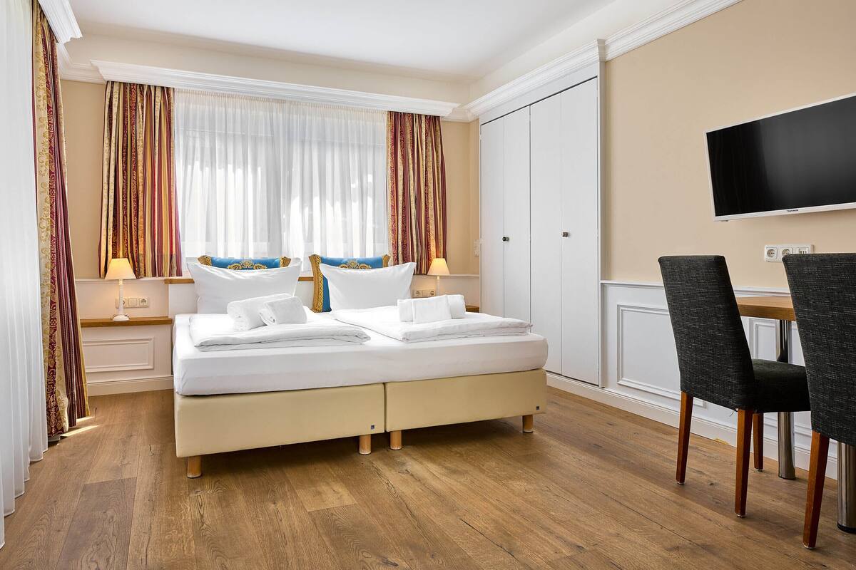 Une chambre d’hôtel avec un lit, un bureau et une télévision.