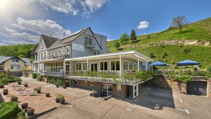 Ein Hotel mit Terrasse, Sitzgelegenheiten im Freien und Blick auf einen Weinberg.