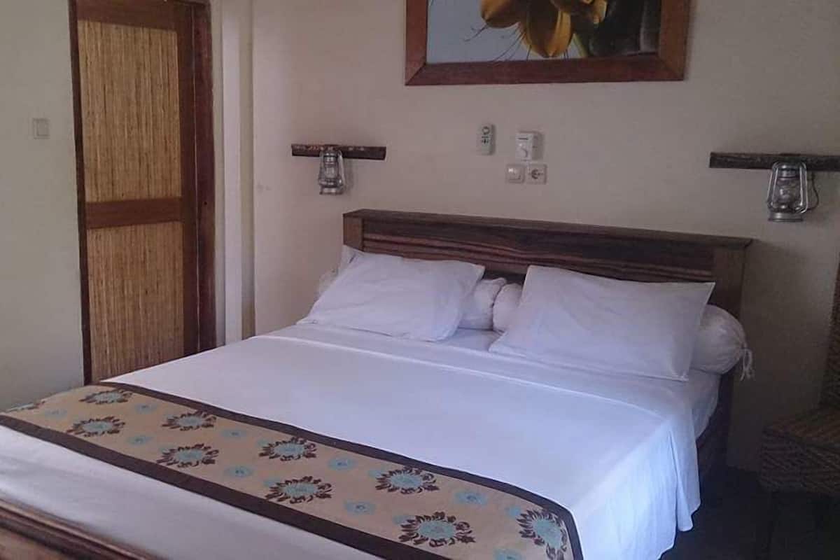 A bed with a patterned bedspread, a wooden headboard, and two wall-mounted lamps.