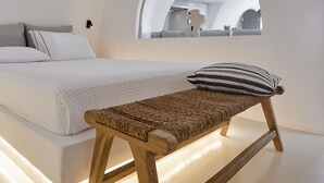 Ein modernes Schlafzimmer mit einem großen Bett, einer hölzernen Bank und einem Oberlicht.