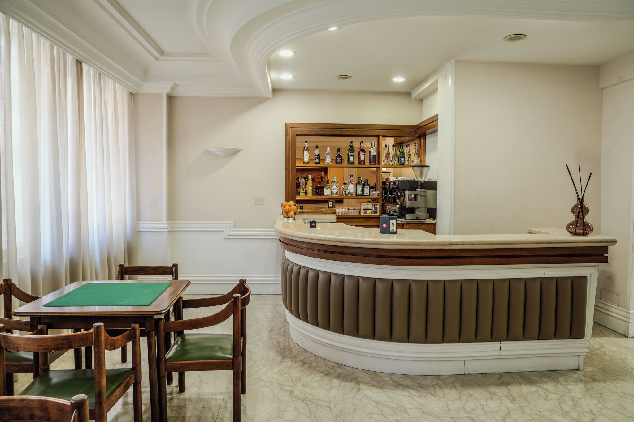 Un hall de hotel con mostrador de recepción, zona de bar y mesa de billar.