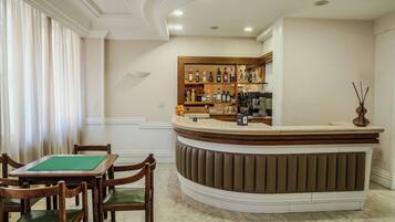Un hall de hotel con mostrador de recepción, zona de bar y mesa de billar.