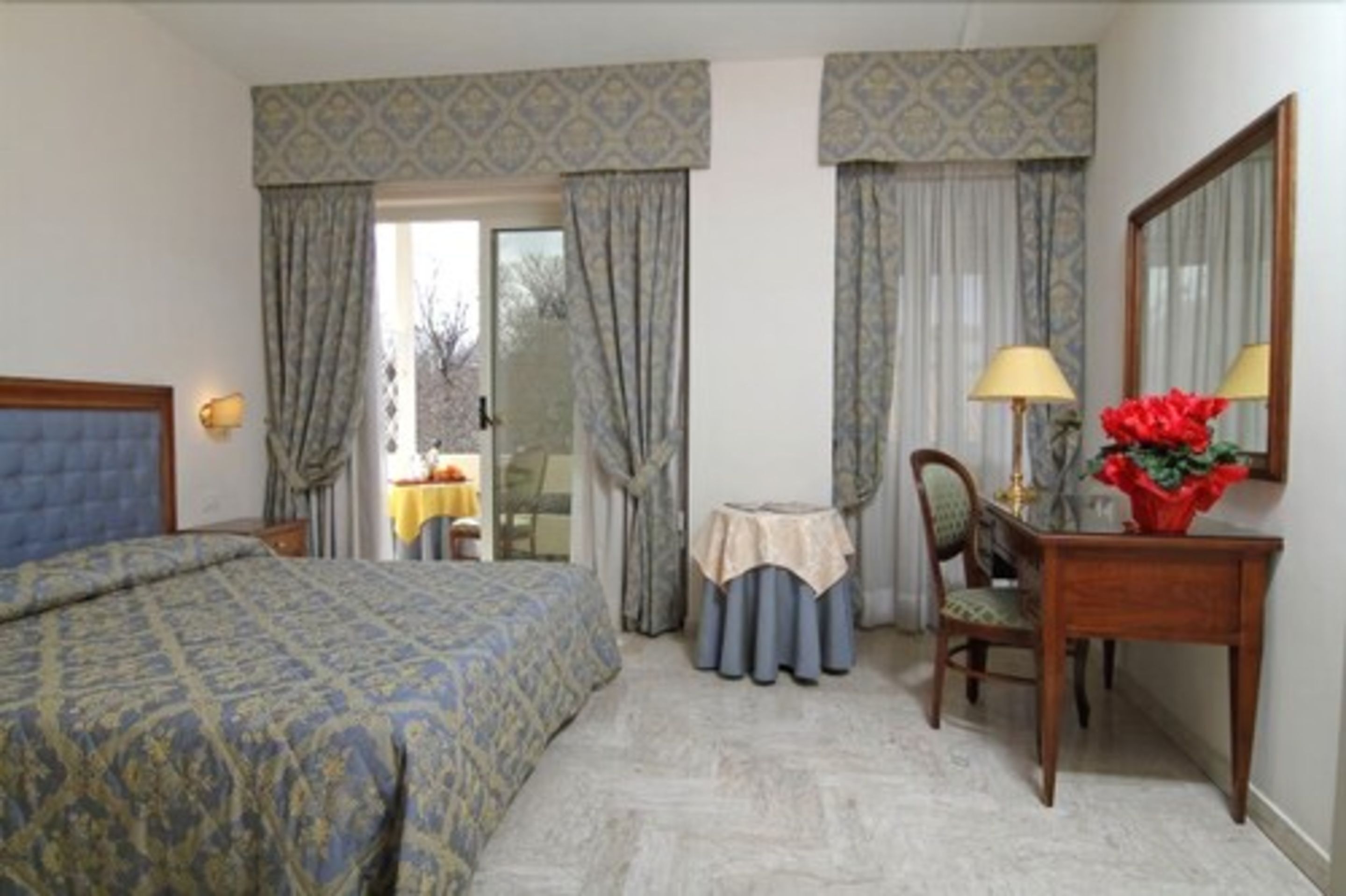 Une chambre d’hôtel comprenant un lit, un bureau avec une chaise, une petite table et un miroir.