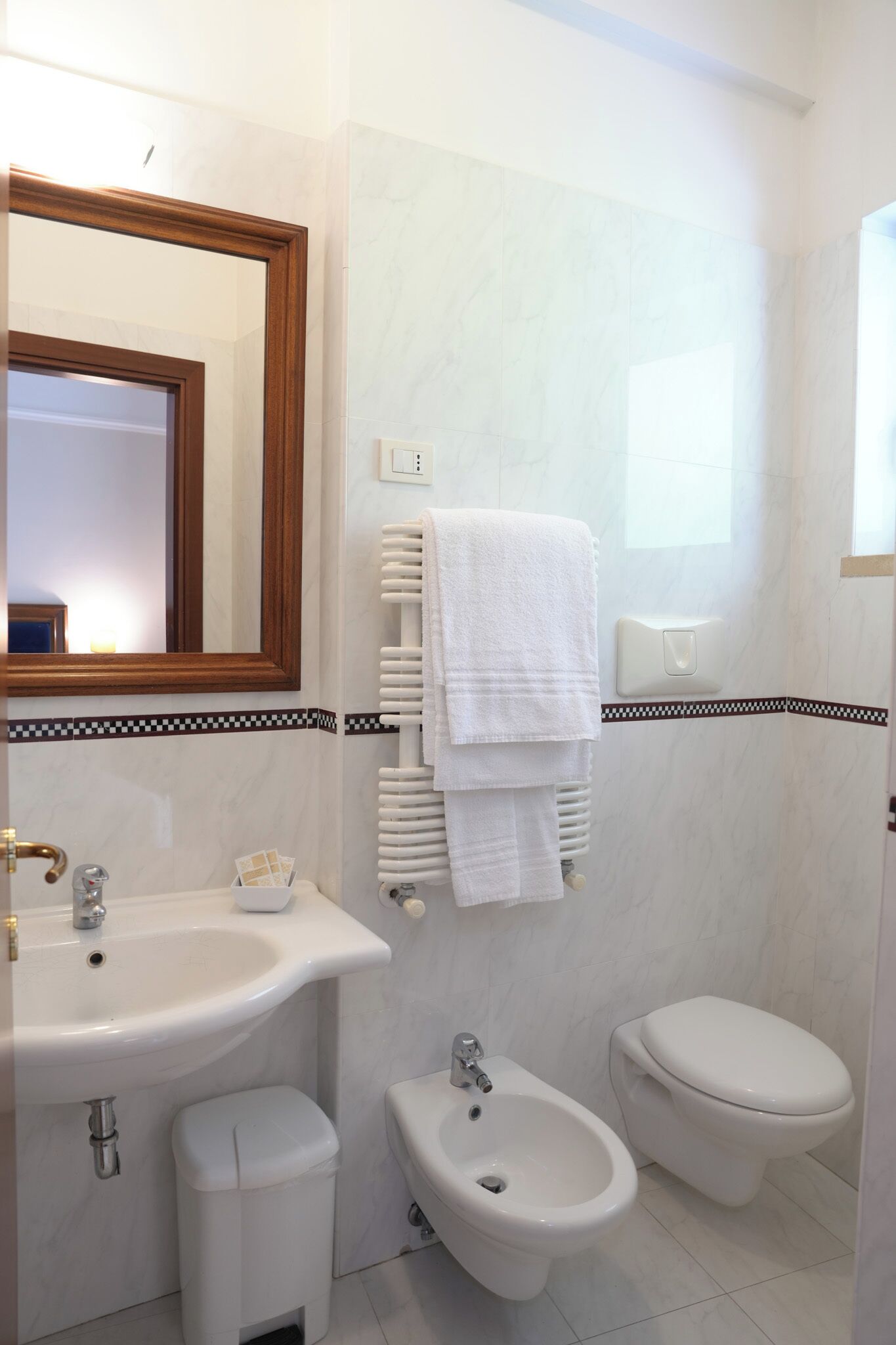 A bathroom with a sink, bidet, toilet, and a mirror.