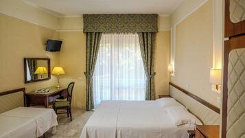 Une chambre d’hôtel avec deux lits, un bureau avec une chaise, une télévision et une fenêtre avec des rideaux.