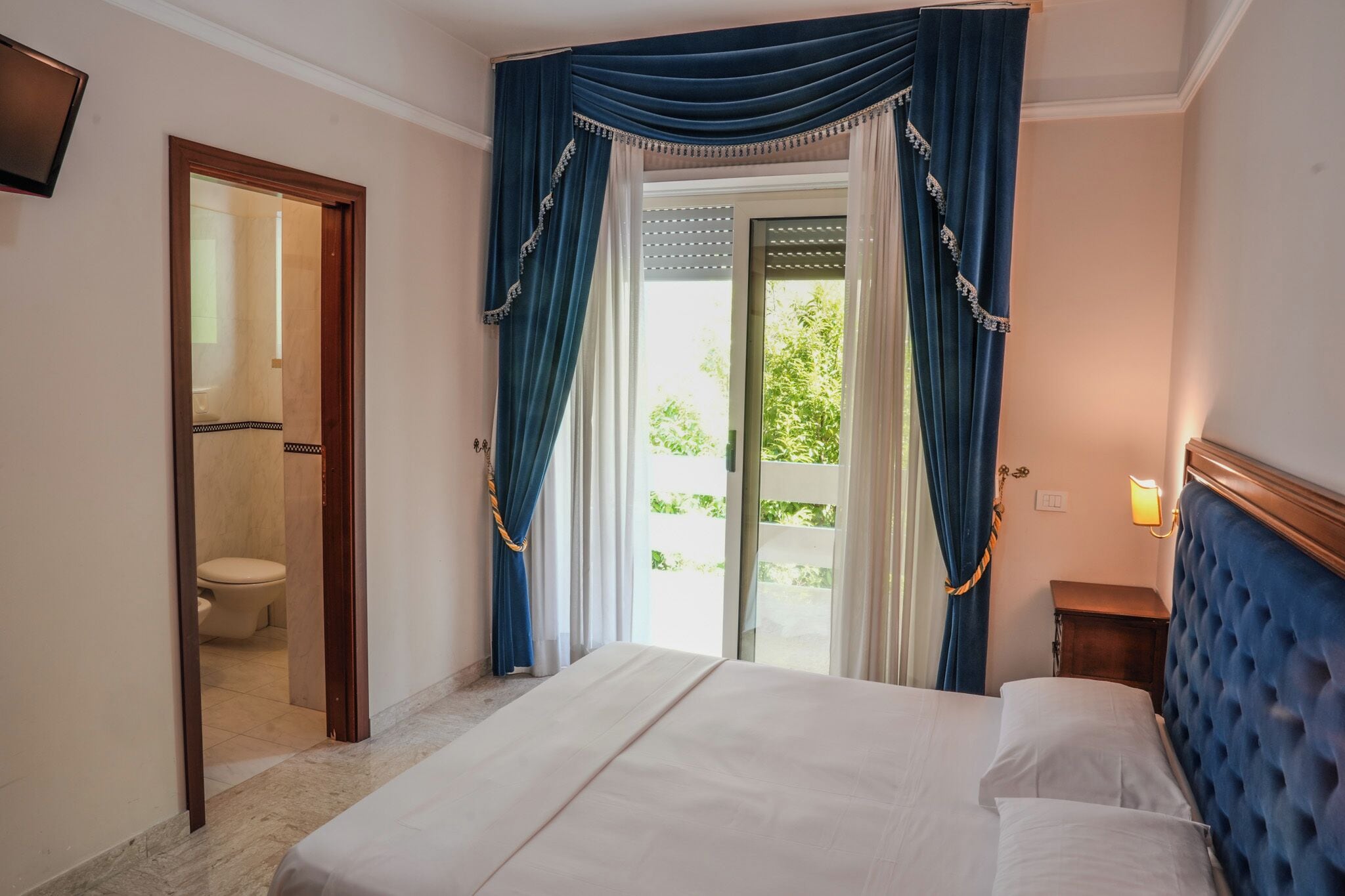 Ein Hotelzimmer mit Bett, Bad und Blick auf Grünfläche.