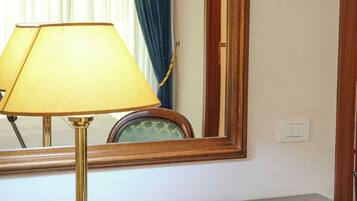 A wooden desk with a brass lamp, a mirror, and a plate with pastries and a rose.