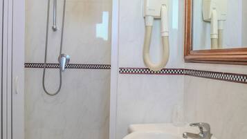 Une salle de bain avec une douche, un lavabo et un miroir.