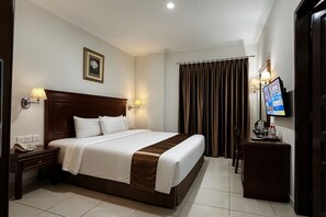 Une chambre d’hôtel avec un grand lit, des lampes de chevet, une télévision et un bureau équipé d’un téléphone et d’une machine à café.