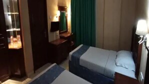 A hotel room with a bed, a desk, a chair, a mirror, and a window with curtains. - Antares Medan (Medan)