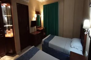 A hotel room with a bed, a desk, a chair, a mirror, and a window with curtains. - Antares Medan (Medan)