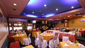 A banquet hall with round tables, chairs, and a stage area. - Antares Medan (Medan)