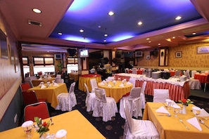 A banquet hall with round tables, chairs, and a stage area. - Antares Medan (Medan)