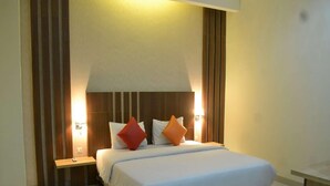 A hotel room with a bed, bedside tables, and wall-mounted lamps. - City Hotel Tasikmalaya (Tasikmalaya)