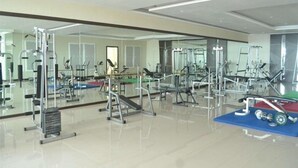 A gym with various exercise equipment, a mirrored wall, and a clean, polished floor. - City Hotel Tasikmalaya (Tasikmalaya)