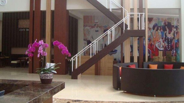 A lobby with a staircase, a reception desk, and a seating area. - City Hotel Tasikmalaya (Tasikmalaya)